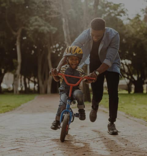Dad teaching his kid how to ride a bike in a safe community