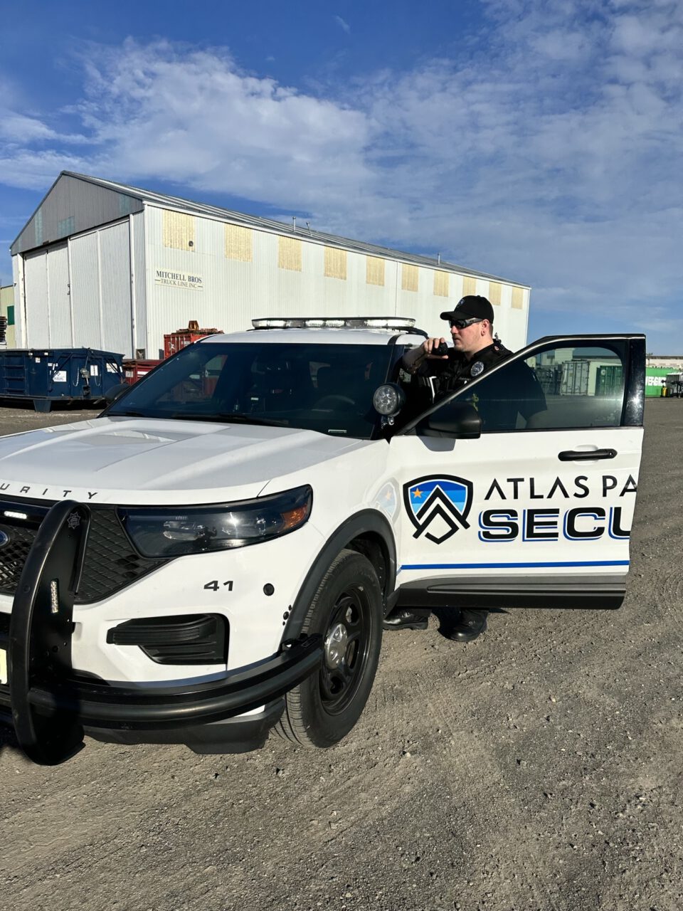 Atlas Pacific Security patrol officer standing at his car with the door open.