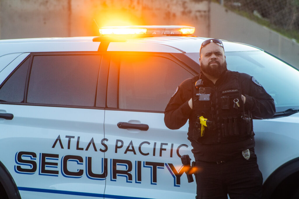 An Atlas Pacific Security patrol officer standing next to his patrol vehicle.